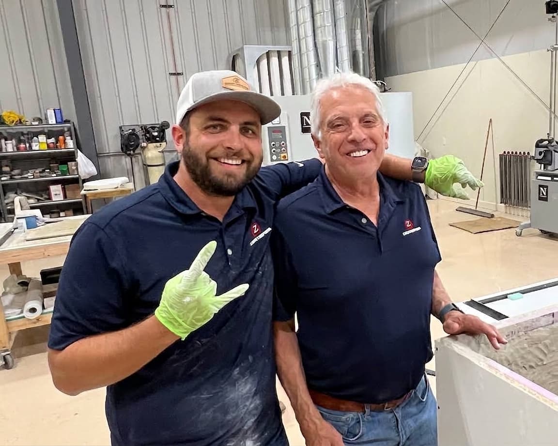 Dario and Ed in the Concrete Countertop Solutions shop, standing beside a freshly cast slab